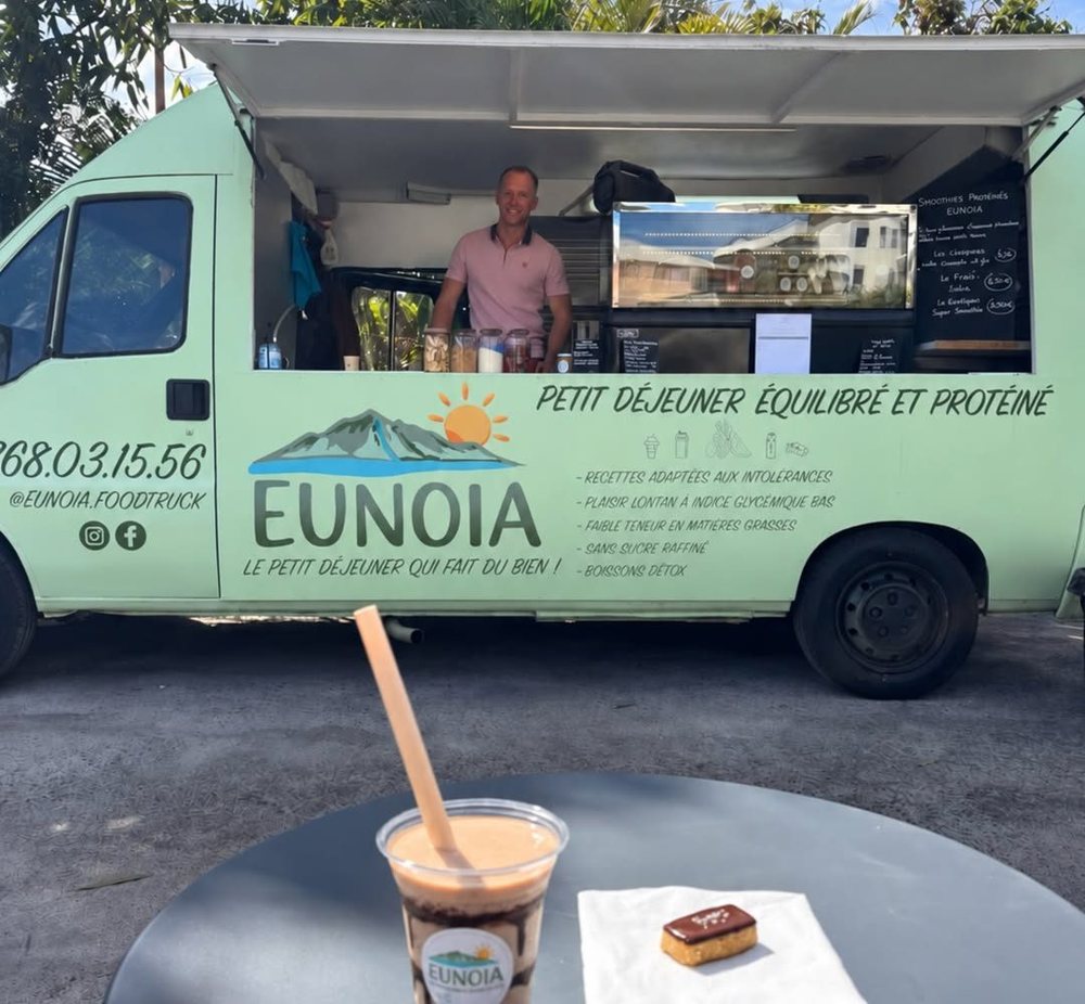 Le food truck vert menthe Eunoia, fenêtre ouverte, avec un smoothie et une bouchée au premier plan